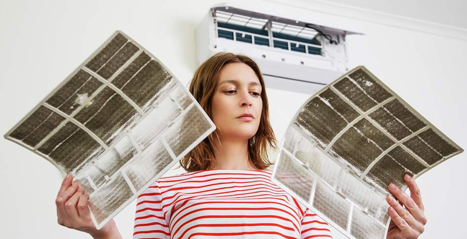 Woman looking at two dirty air filters. Understanding MERV, arrestance, CADR, and other acronyms will help you decide which air filter is right for you.